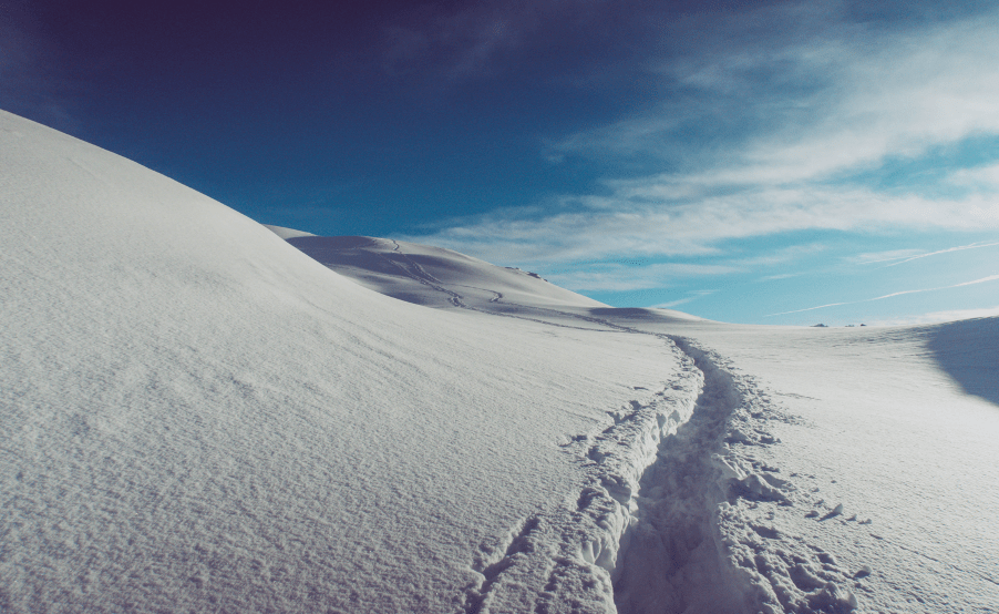 A single foot track through a snowy mountain landscape.
