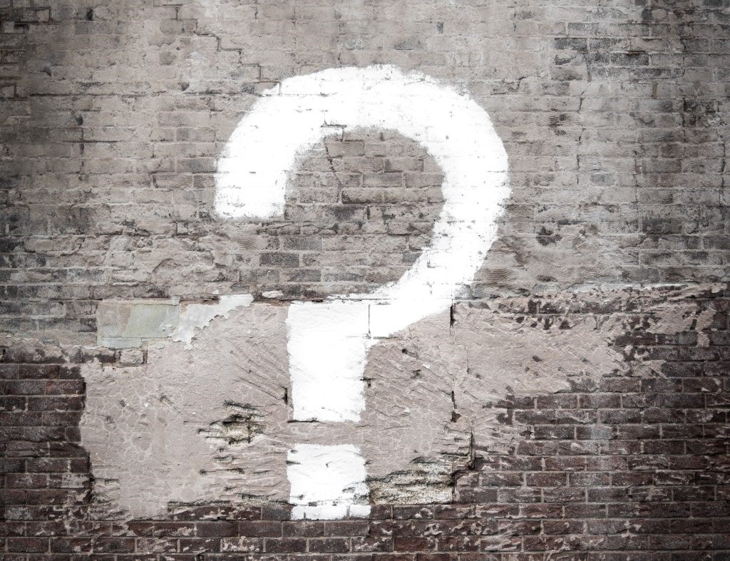 A spray painted question mark on a brick wall