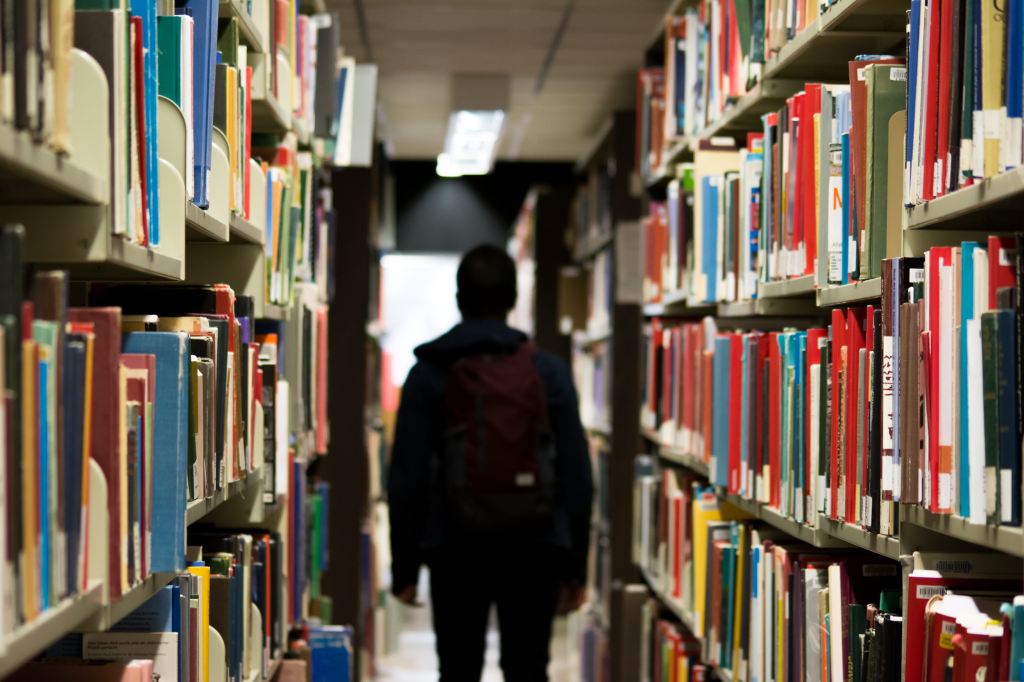 a person in a university library, in silhouette/shadow, fading into the background.