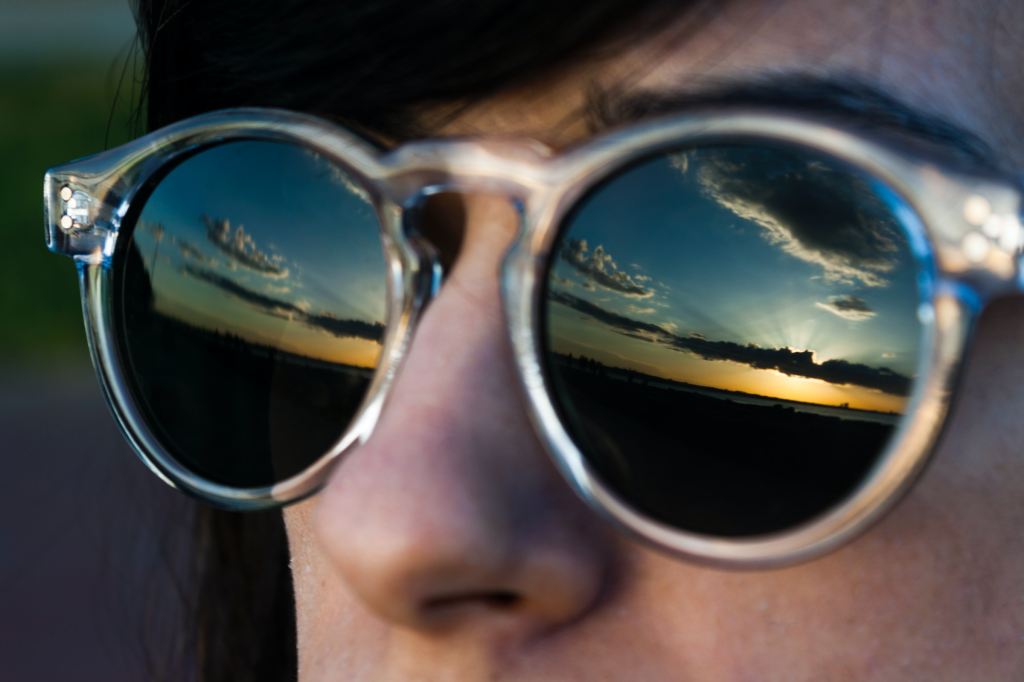 Woman wearing sunglasses with reflection of sunny skies