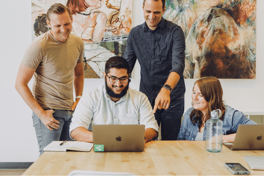 four people collaborating around a laptop
