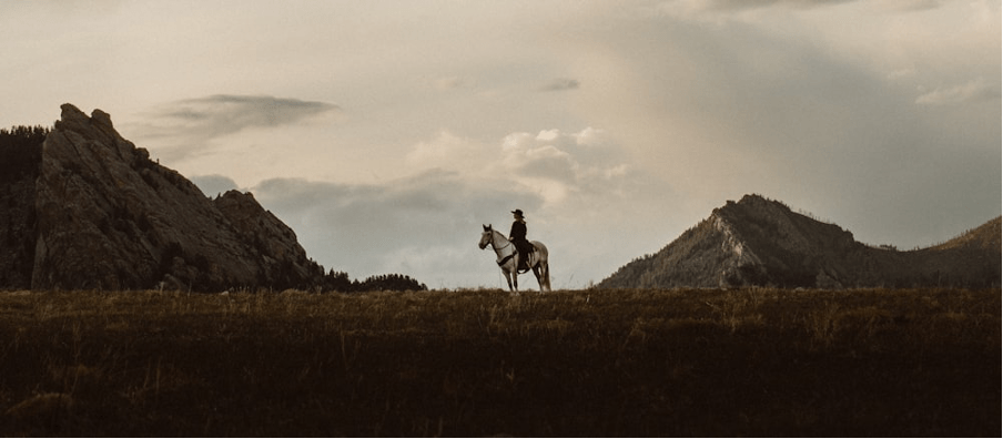 A lone person on horseback in the distance in a mountainous landscape