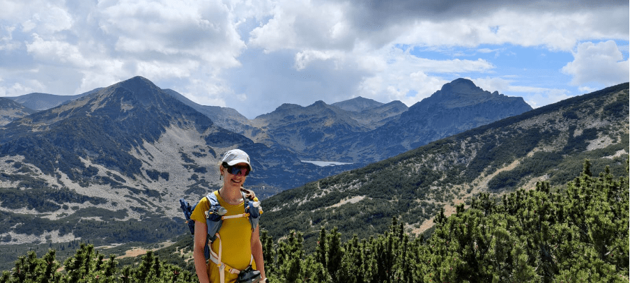 Gabriella in hiking gear, on a sunny day in the mountains.