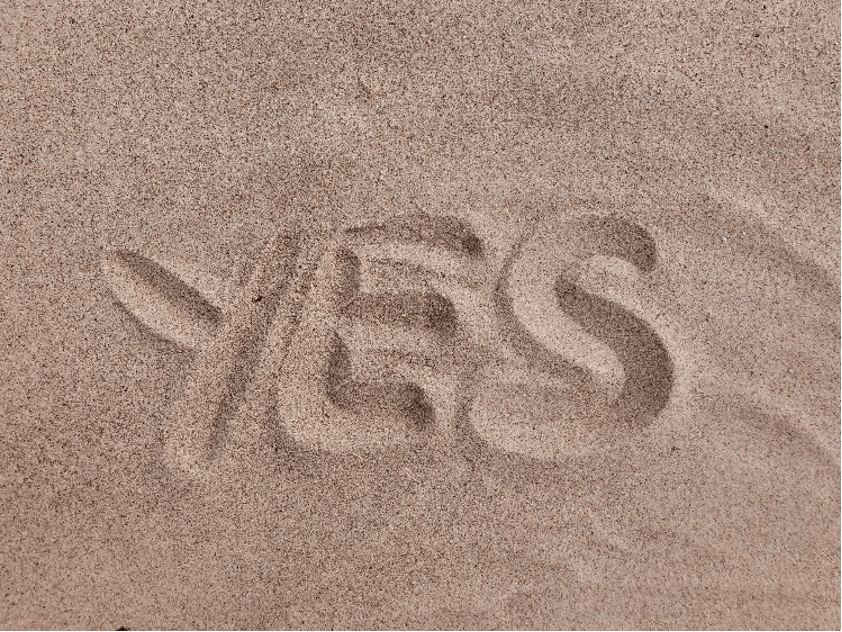 The word YES written in sand.