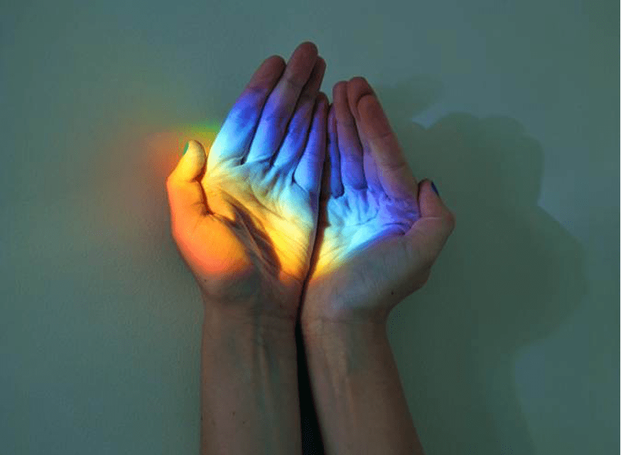 cupped hands hold a rainbow reflected from a prism