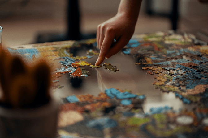 A hand places jigsaw pieces.