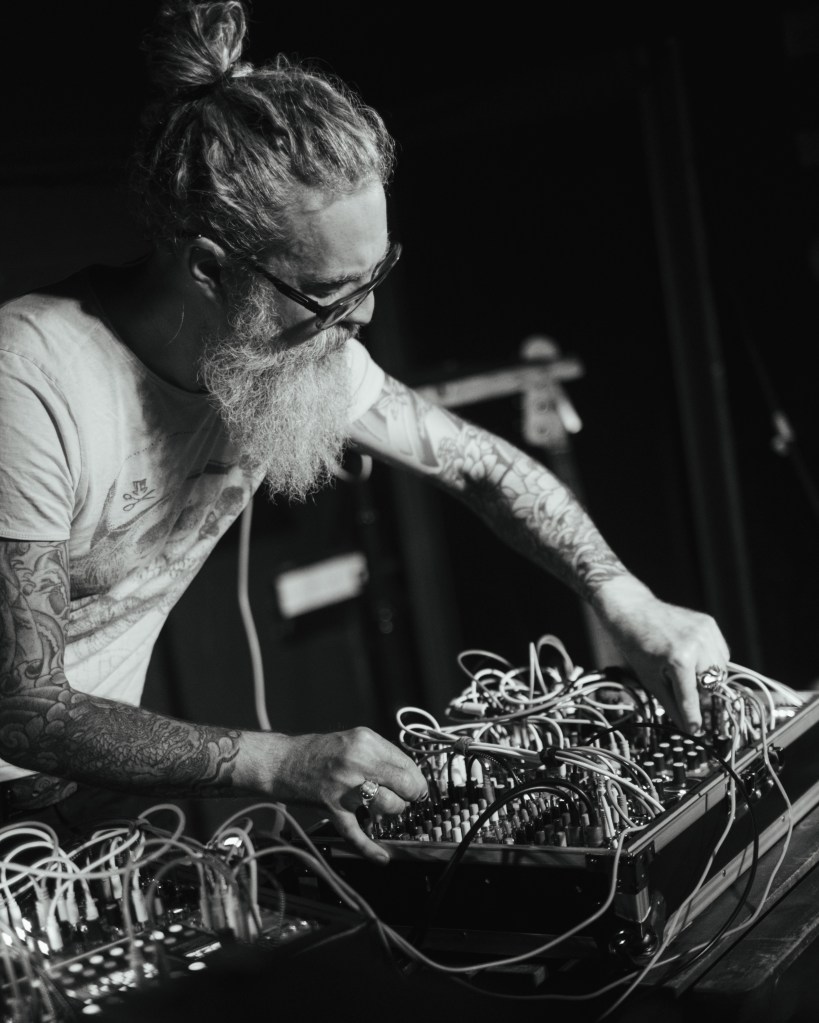 Black and White Image of Fraser Rowan (Ty Lumnus) performing live with his modular synth.