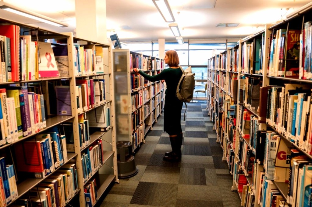 A person browses bookshelves in a university library
