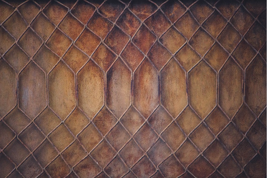 a rusted chain link fence with many equally sized square links but the centre shows a row of wider looser links in the chains