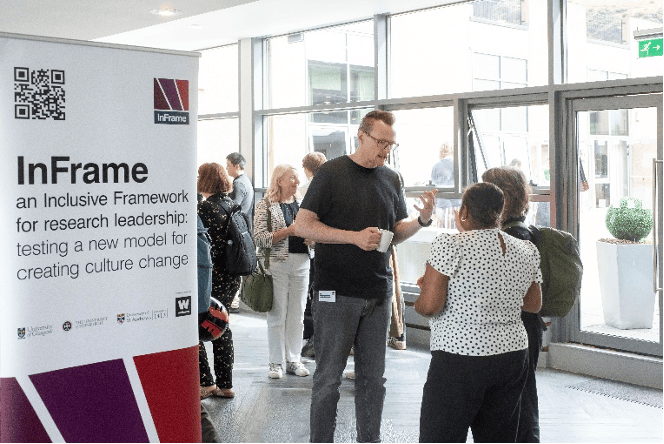 Participants networking and chatting at an InFrame event beside a project banner, illustrating cross-institutional collaboration, community building, and research culture engagement.